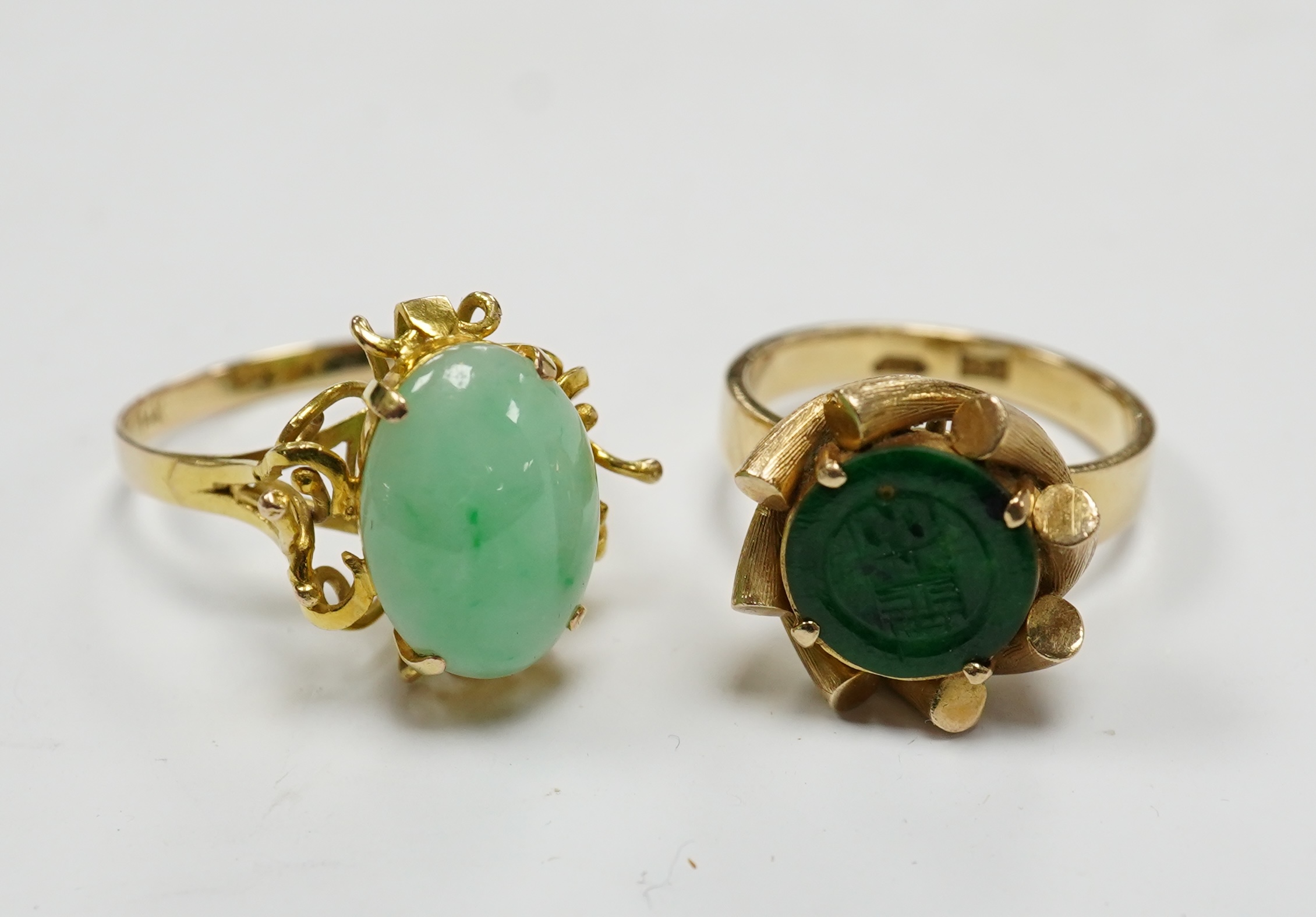 A Chinese 14k and single stone oval cabochon jadeite set ring, size P and a similar 14k and spinach green jade mounted ring, size O, gross weight 11.1 grams. Condition - fair to good